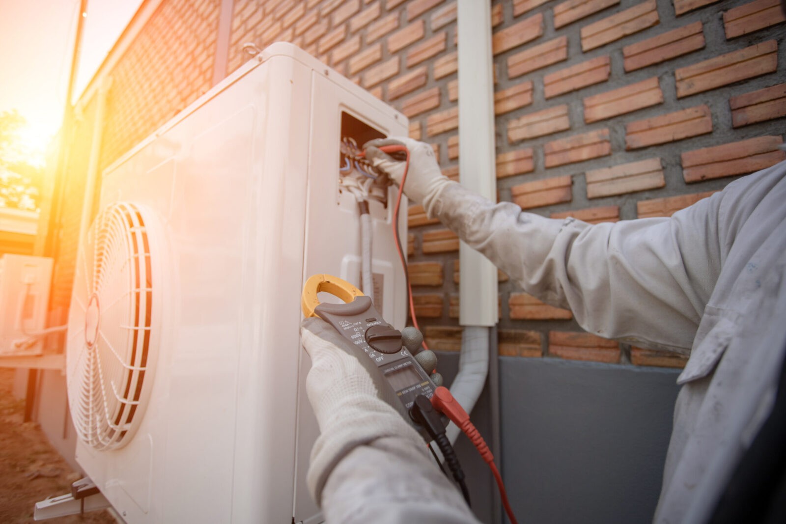 Technician servicing an outdoor air conditioning unit with tools.